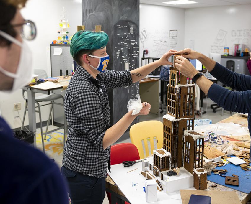 Students with face masks carefully building gingerbread Cathedral of Learning