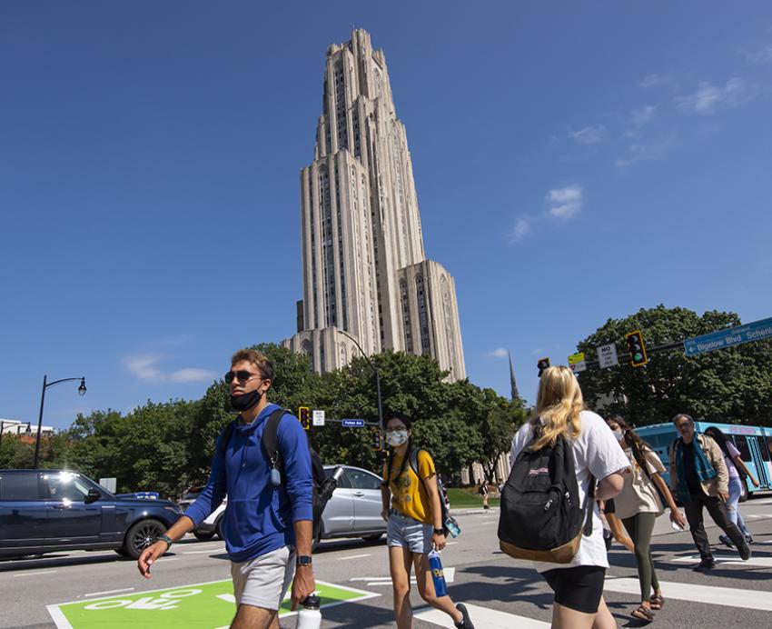 Students crossing a street in front of the Cathedral of Learning
