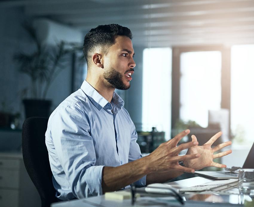 Frustrated man with blue shirt reacting to computer on his desk