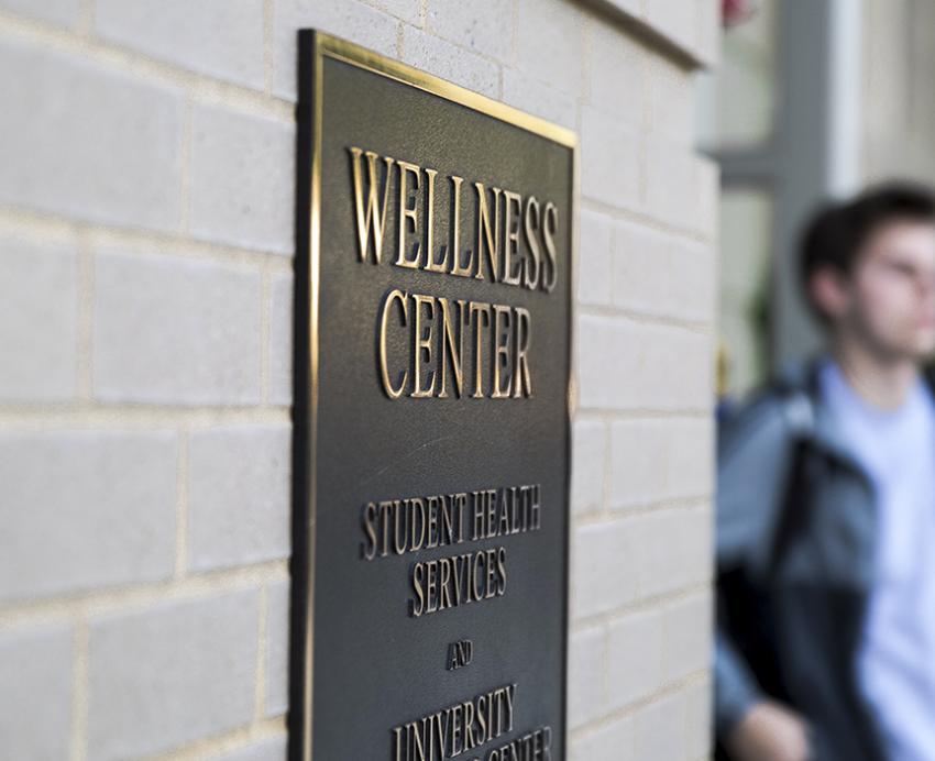 Wellness Center nameplate with person standing next to it