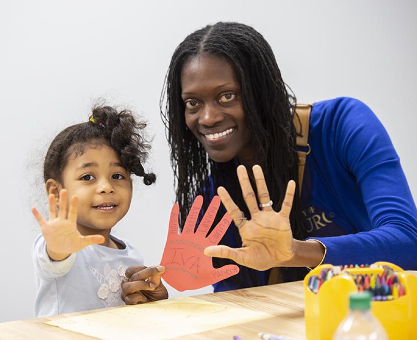 Valerie Kinloch holding up her hand and smiling with a young girl