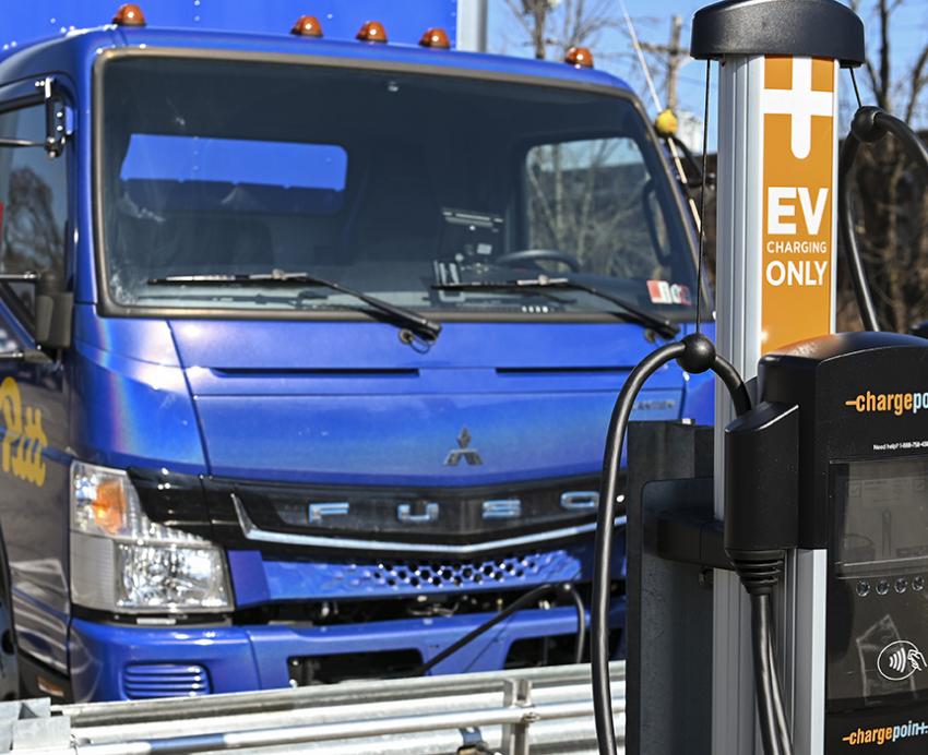 Blue Pitt box truck parked next to EV charging station.