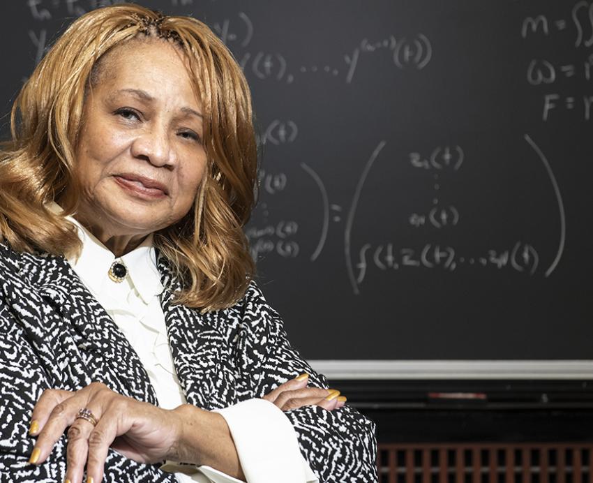 Elayne Arrington standing with her arms folded in front of chalkboard