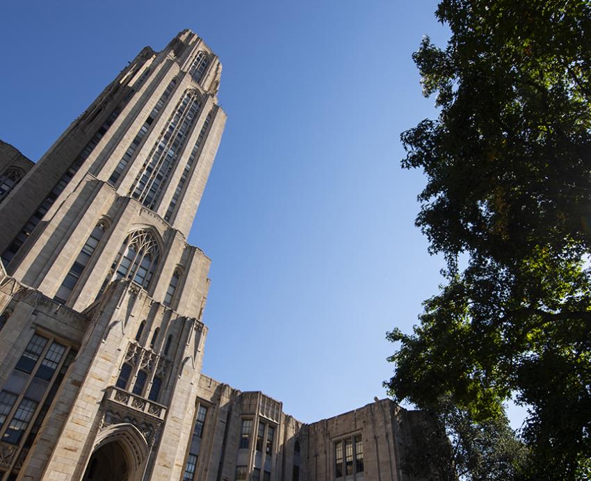 Cathedral of Learning next to trees on a sunny day 