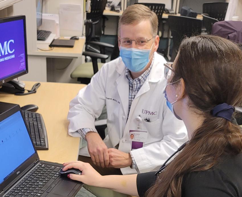UPMC doctor speaking to student at a desk 