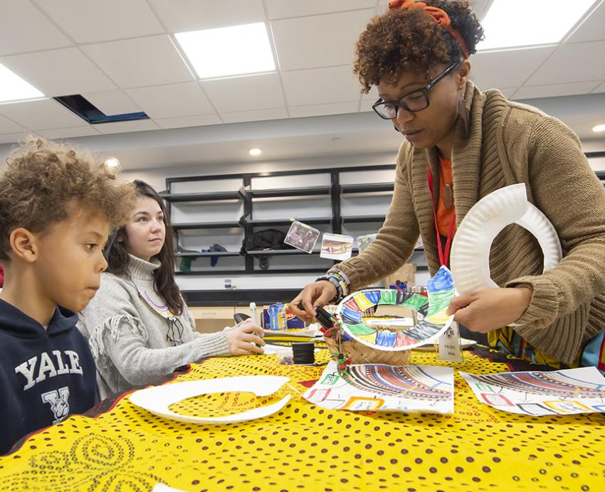 Woman teaching children at a table with colorful crafts