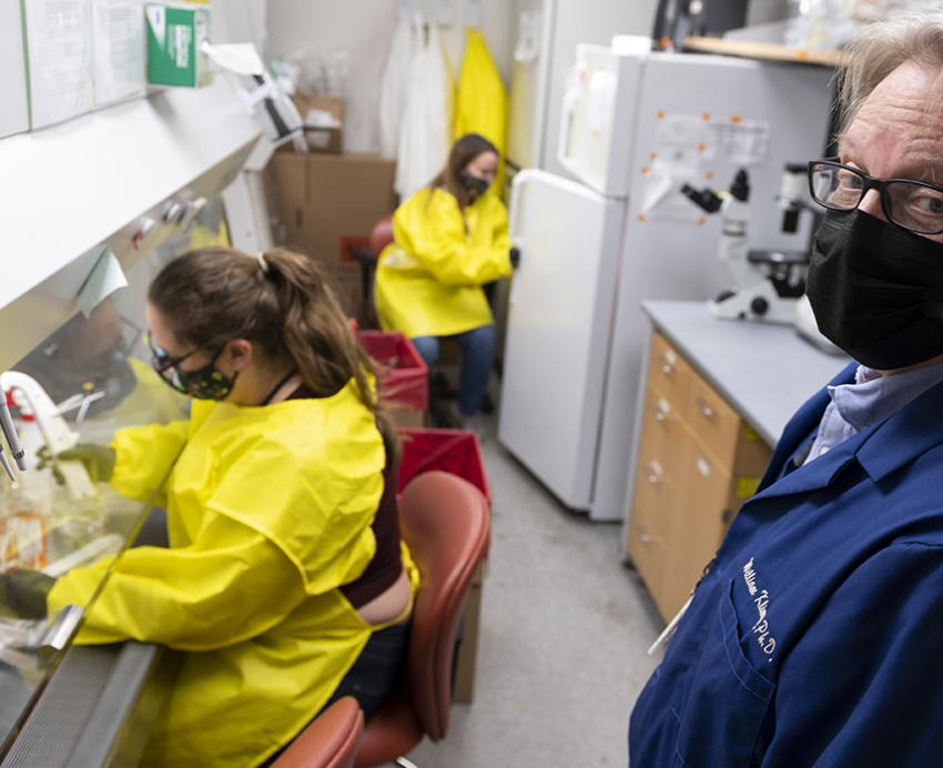 William Klimstra and workers in yellow gowns in a lab