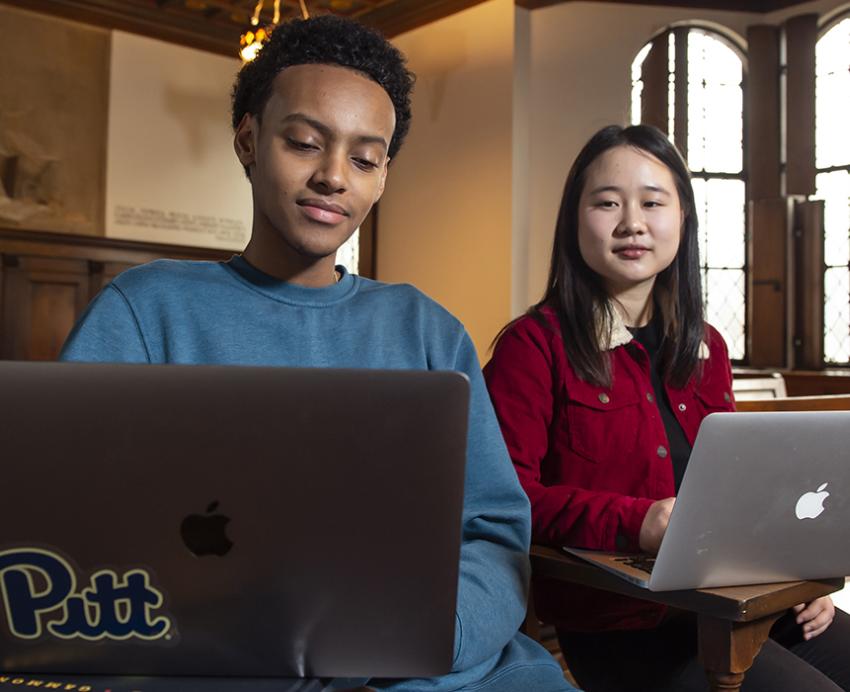 Two students working on laptops in nationality room