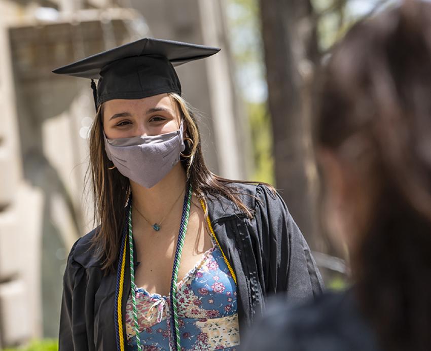 Student in cap and gown posing for photo outside
