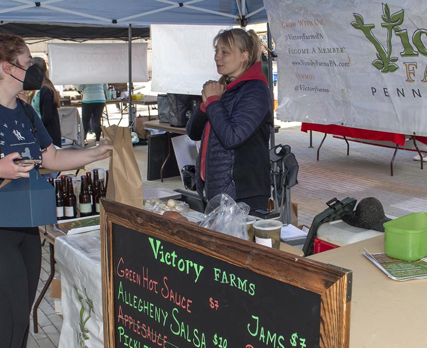 Student purchasing from Victory Farms stand at farmers market
