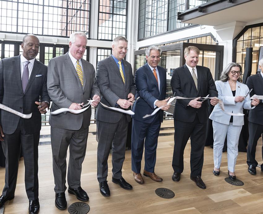 Seven people in suits cutting ribbon during opening