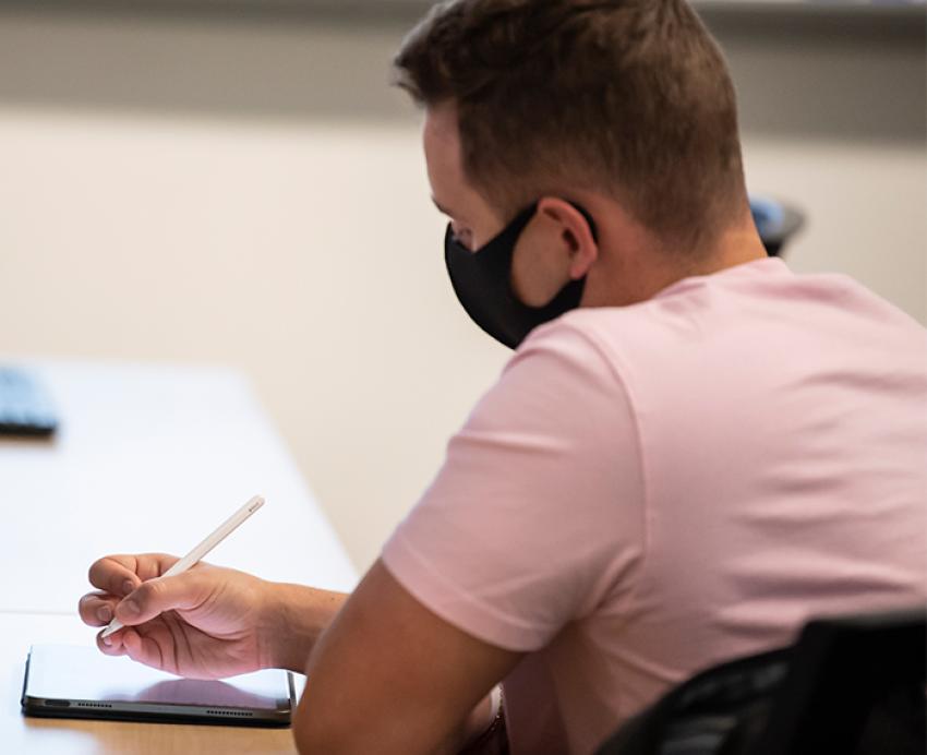 a person in a pink shirt writing on a tablet