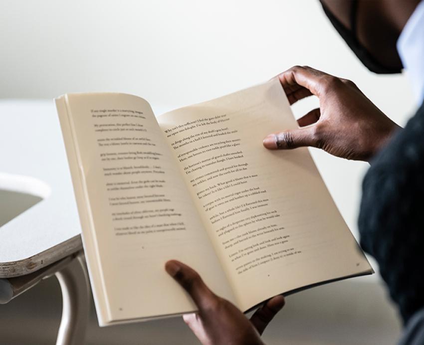 a person holding an open book of poetry