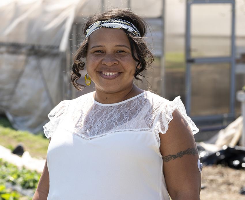 a person in front of a greenhouse and garden