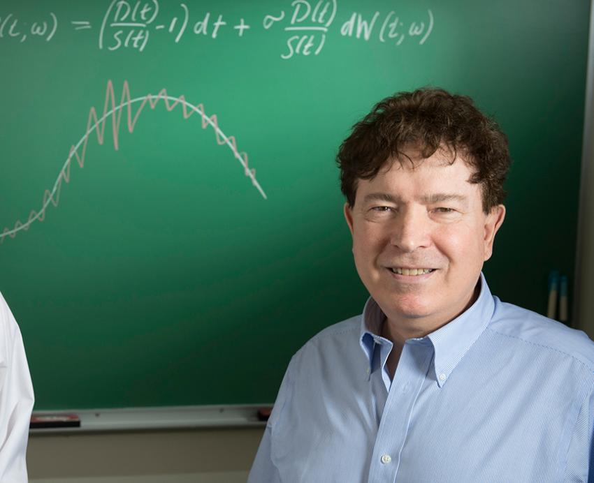 the Caginalps at a chalkboard with figures drawn on it