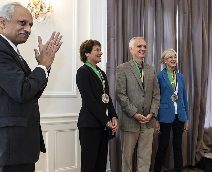 the three winners posing with people clapping near them