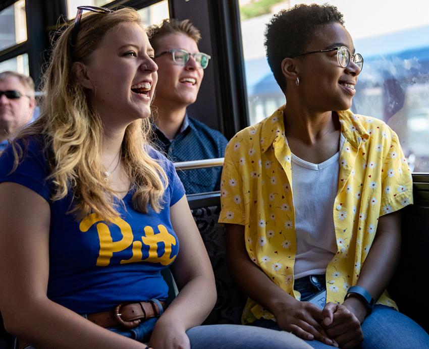 students in Pitt gear riding a bus