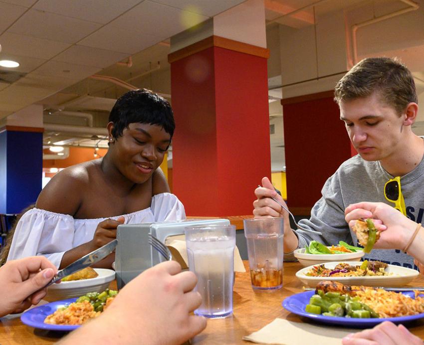 four students gathered around a table eating