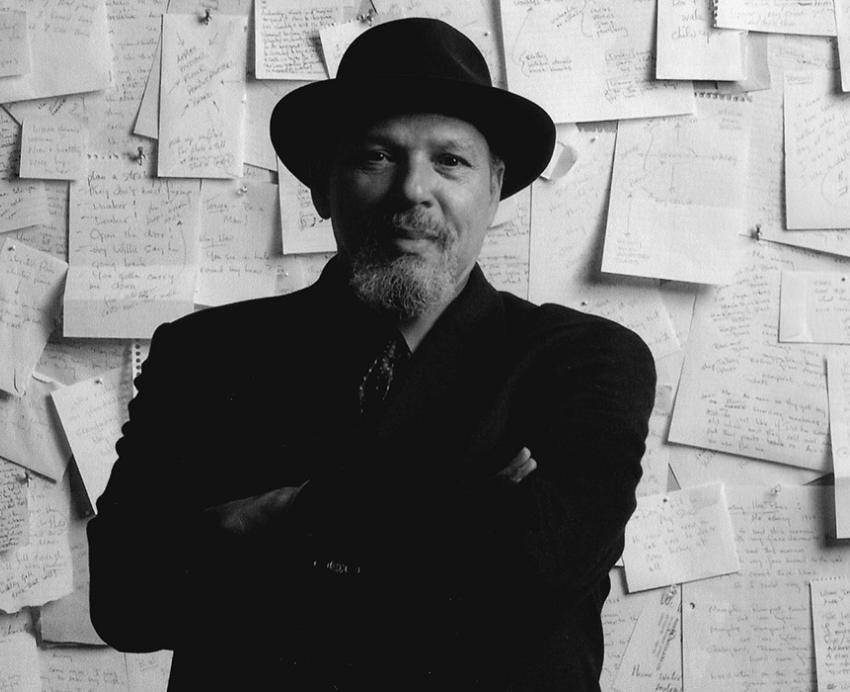 Wilson standing in front of a wall papered with notebook pages