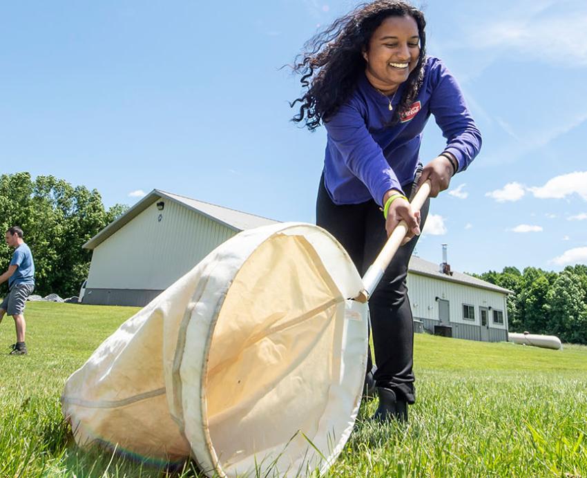 a smiling person with a big net in a field