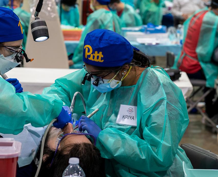 Pitt Dental Medicine folks in scrubs treating a patient
