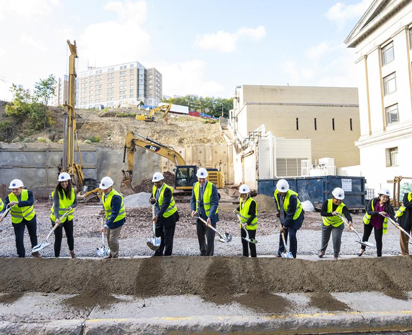 multiple people symbolically digging a shovel of dirt