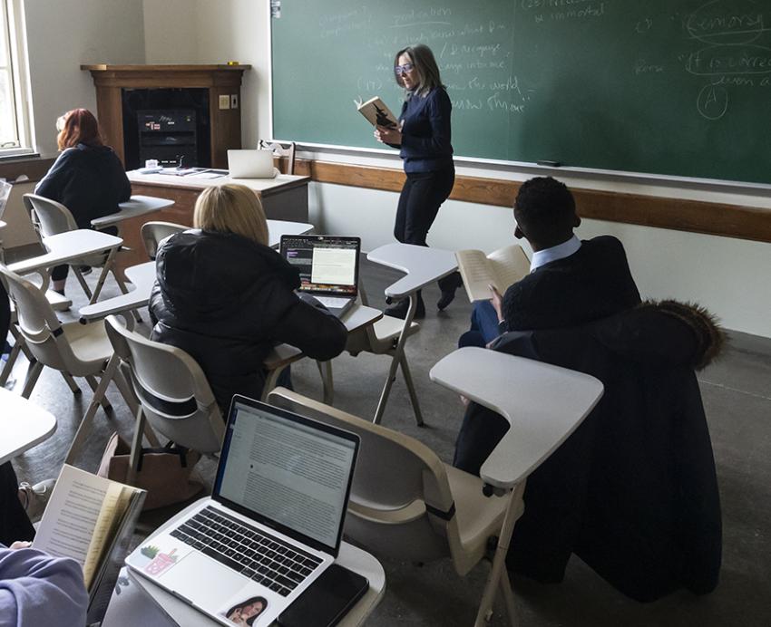 an instructor reading from a book in front of a classroom