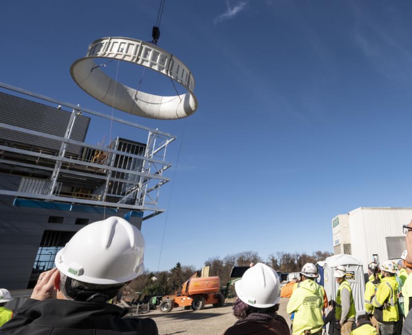 a large cylinder being placed atop a building with a crowd watching