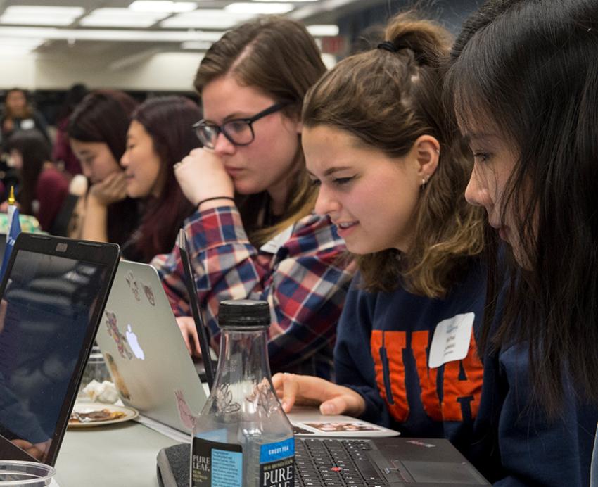 Students work on laptops around a table