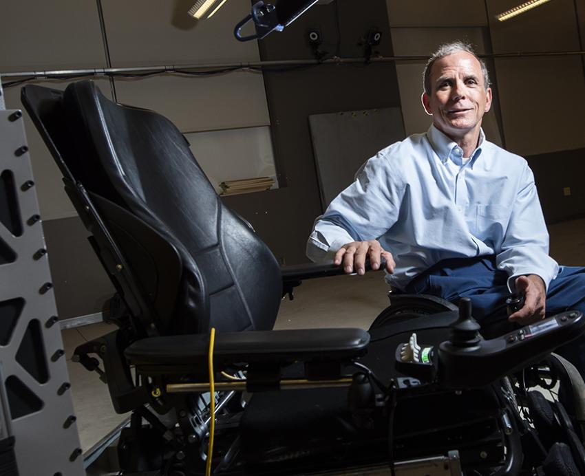Cooper sits next to an electric wheelchair