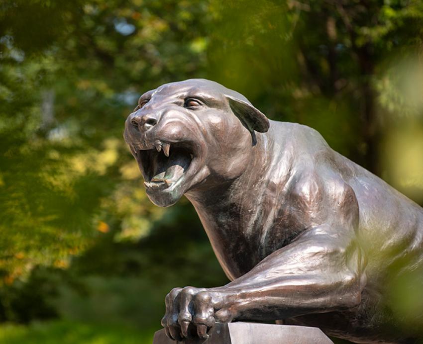 A panther statue in front of green leaves.