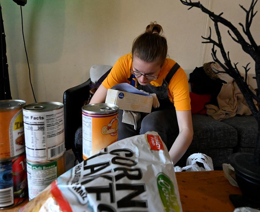 A volunteer in a yellow T-shirt sorts boxes of food donations
