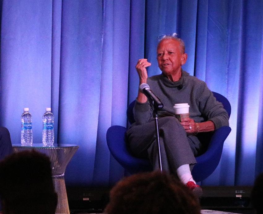 Pickett and Giovanni sit in blue chairs on a stage