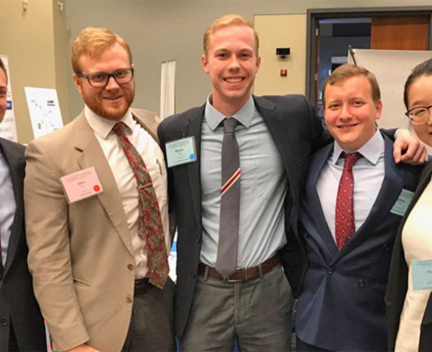 Five students wearing professional attire pose together