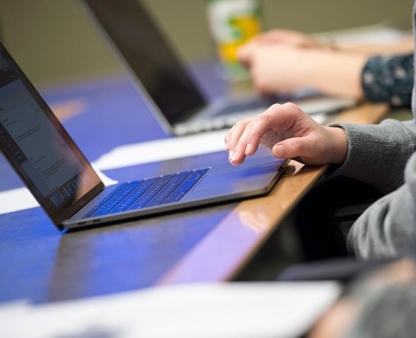 A hand on a laptop trackpad.