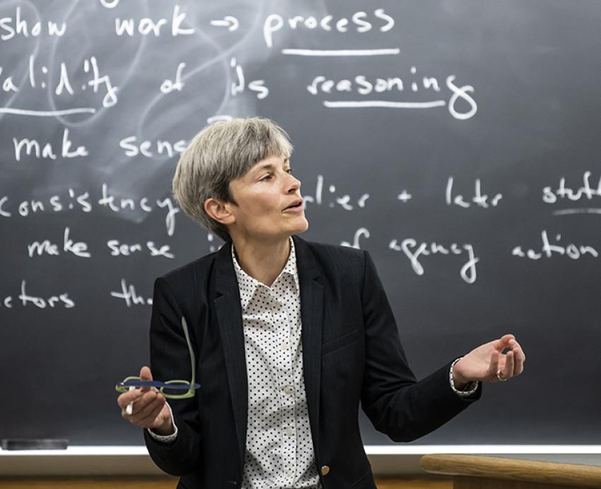Amy Wildermuth speaks in front of a blackboard