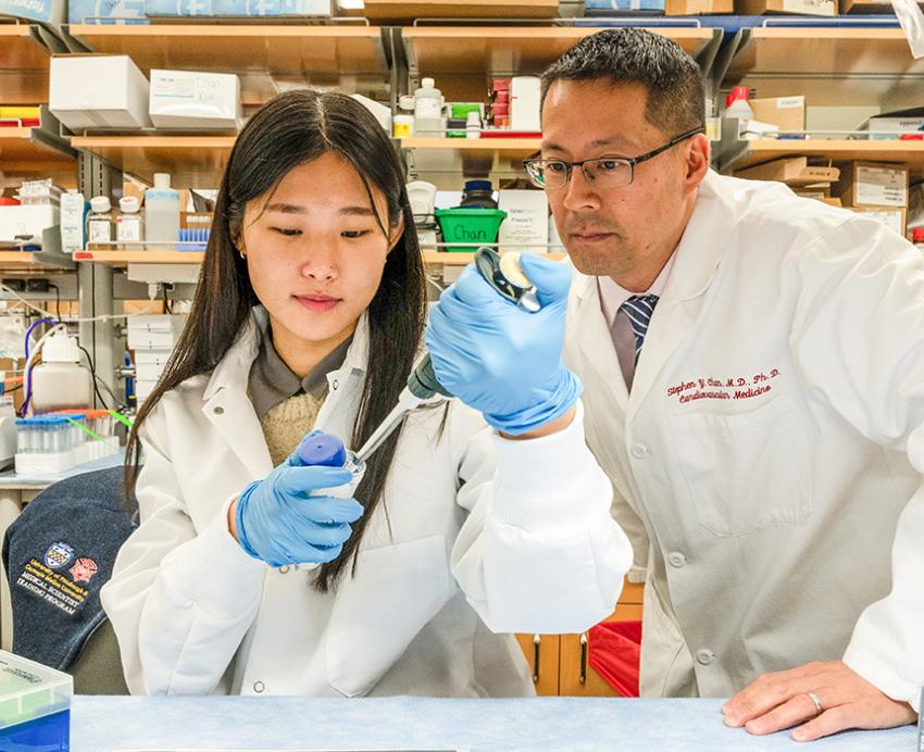 Two people in white coats work in a lab