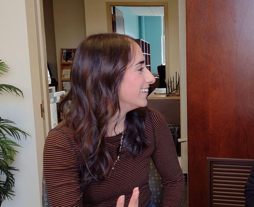 A person in a brown shirt smiles at a person in a black turtleneck