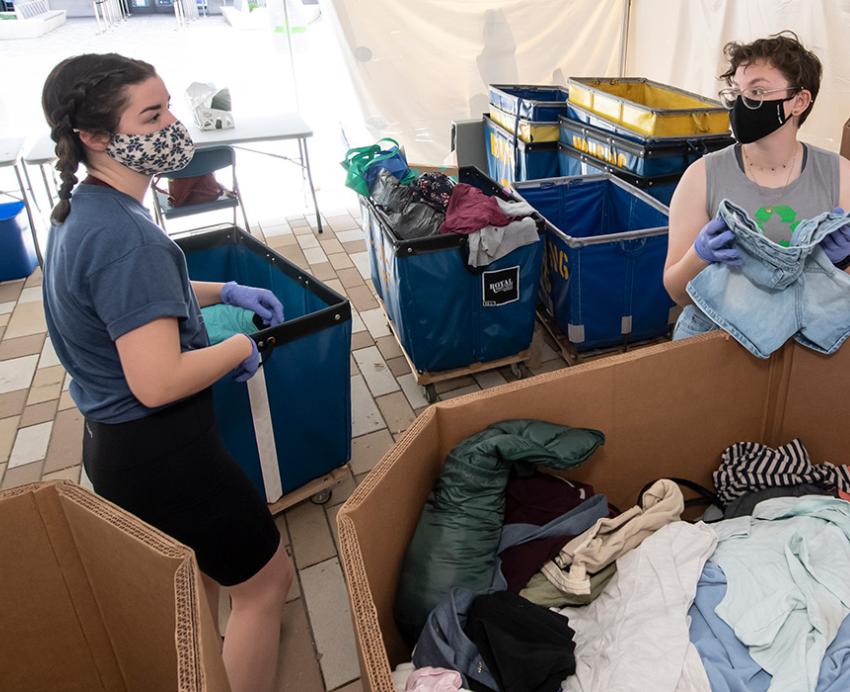 Volunteers fold items from bins of clothes