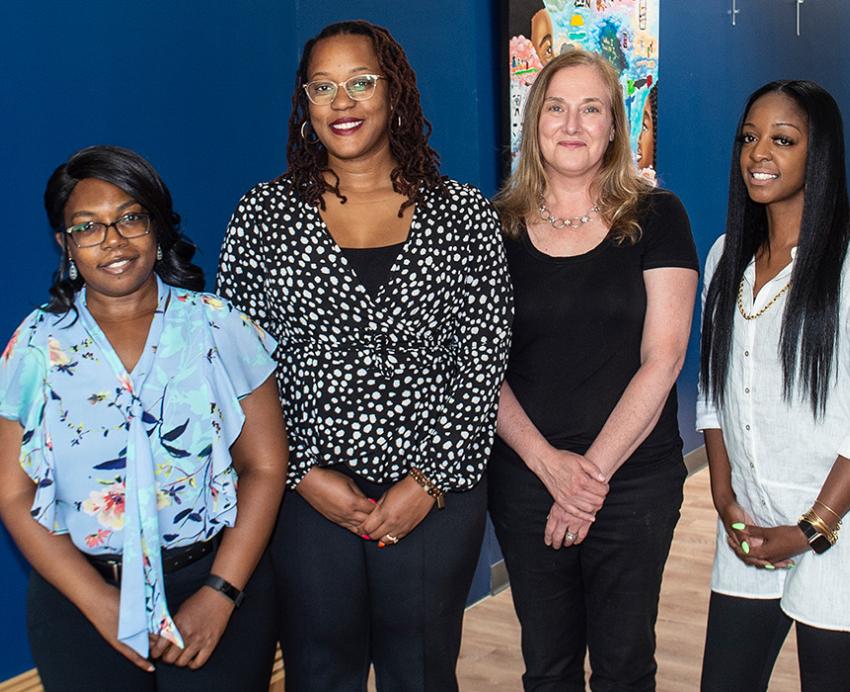 Four people stand in front of a blue wall