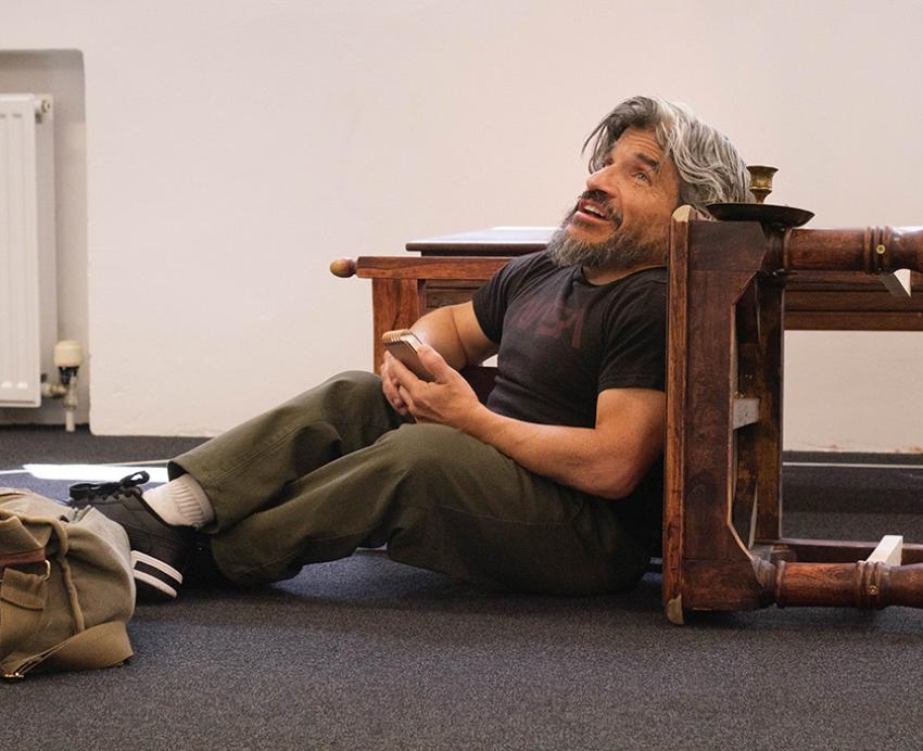 A person with Dwarfism delivers a monologue while leaning on an overturned table