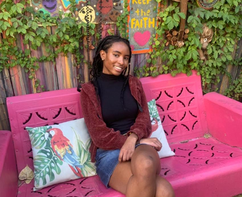 A person sits on a bright pink bench
