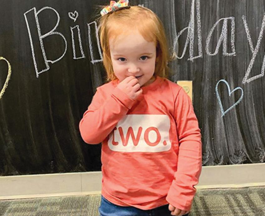A baby in a pink shirt that says Two