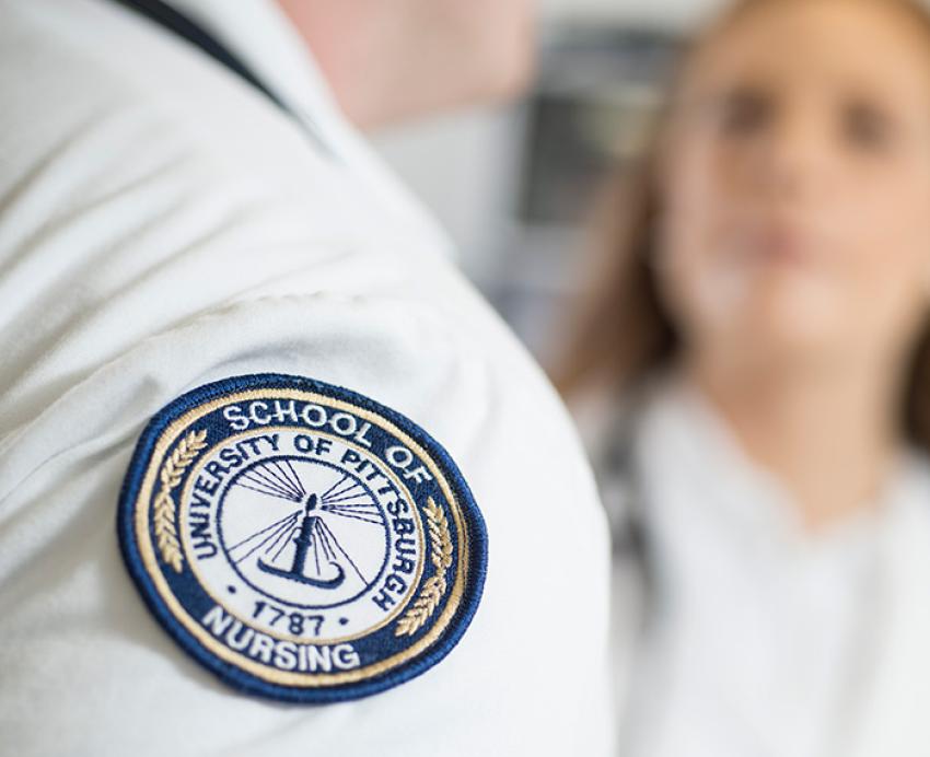 A University of Pittsburgh School of Nursing patch on a white coat