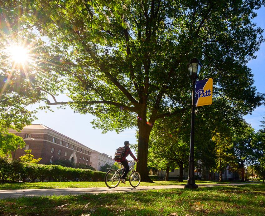 A person bikes on Pitt's campus