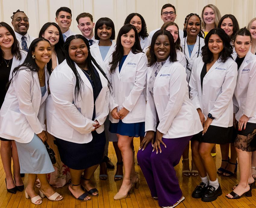 A group of incoming medical students pose in their white coats