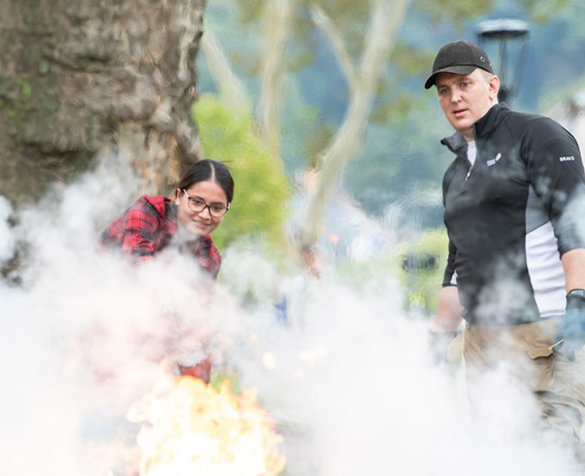 A person discharges an fire extinguisher onto a controlled flame.