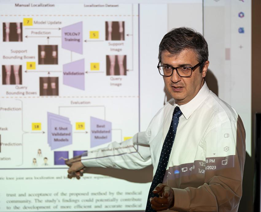 Tafti points at a projected presentation