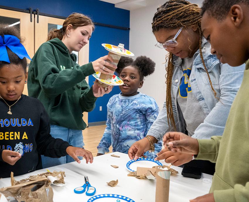 Volunteers help students make crafts with toilet paper holders