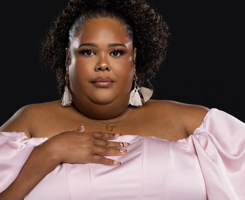 Zuly in a pink dress in front of a black background